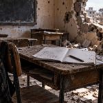 Abandoned school desk in a damaged classroom representing War Child by Kellna Hursle
