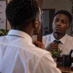 Young man looking at his emotional reflection in a mirror for The Deceit of Trying to Be a Man