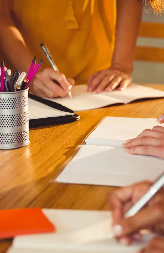 mid-section-of-business-executives-writing-in-book
